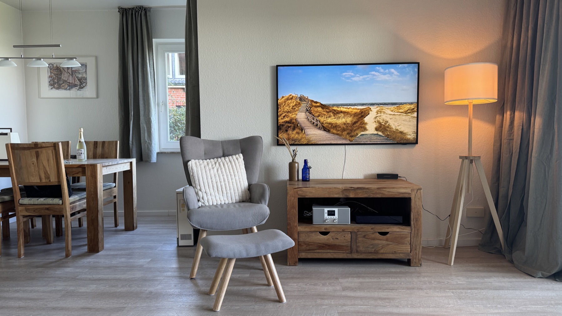 Wohnzimmer mit Sessel, Fernseher und Dünenbild